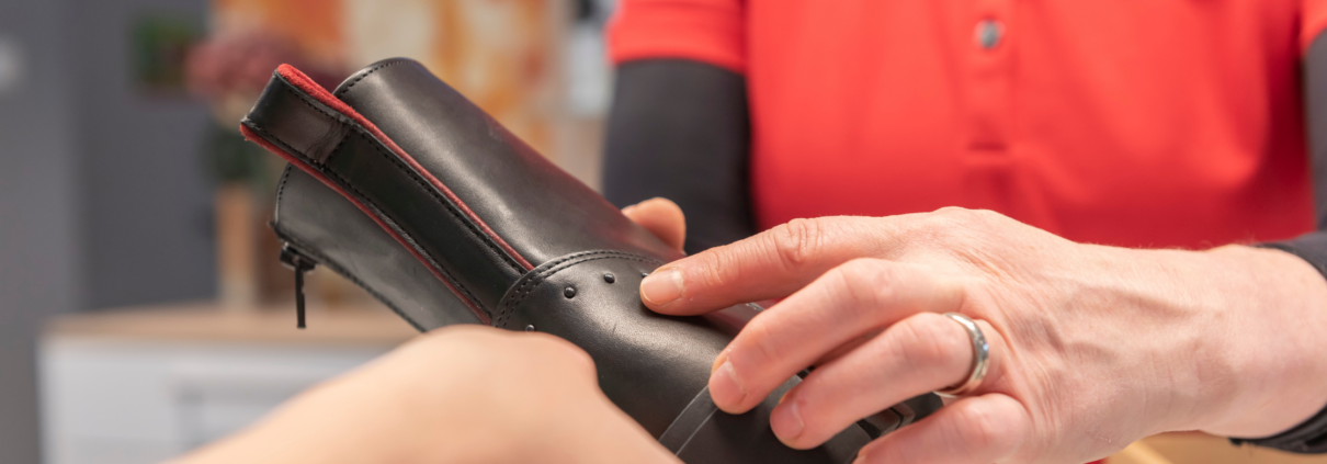 Schuhe werden von einer Mitarbeiterin an eine Kundin weitergereicht, Winterschuhe, Stiefel